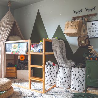 A children's room with a painted mountain-like mural and a high-sleeper bed with a play area underneath