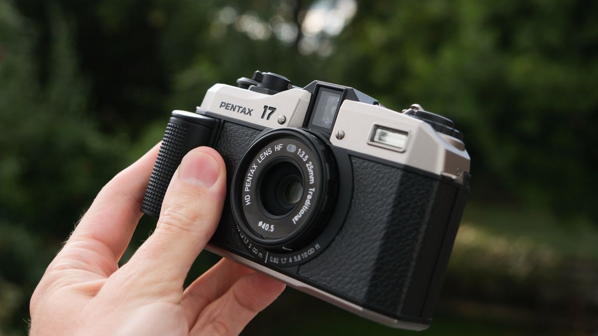 A Pentax 17 film camera held in a hand outside