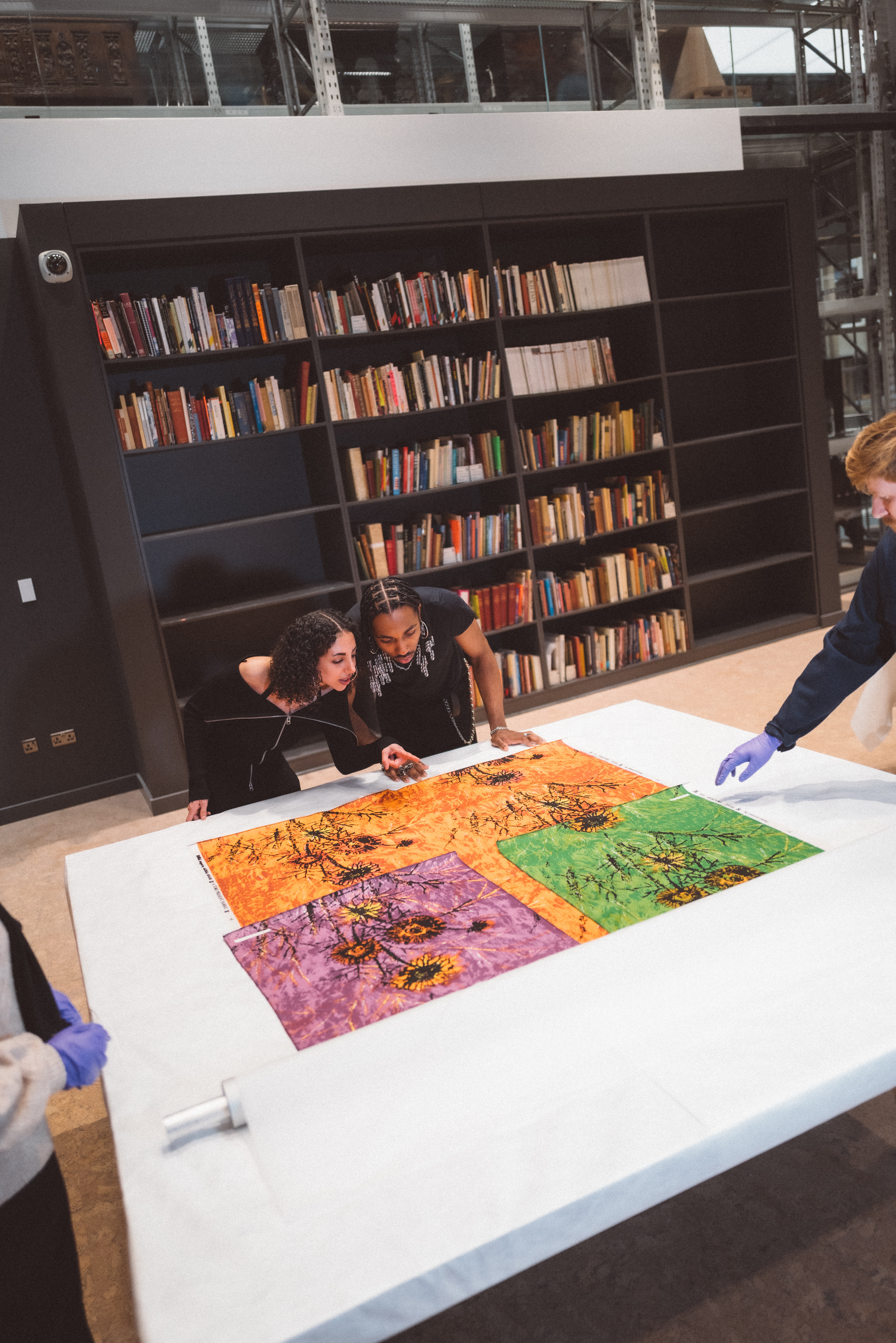 A group of young people observes a series of colorful, sculptural artifacts up close in a museum's specialized unit.