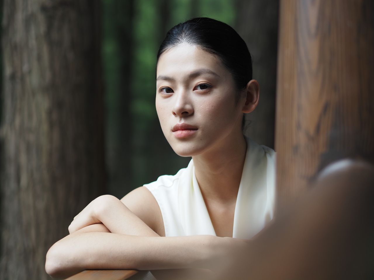 OM System PEN sample gallery: Female model in white dress, set among wooden pillars