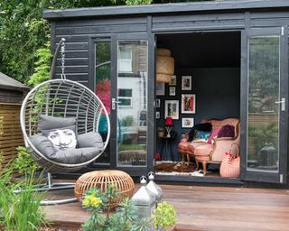modern she shed with decked porch and hanging chair