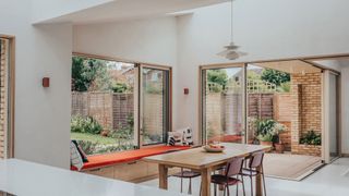 modern kitchen diner extension with corner sliding doors and sliding window seat
