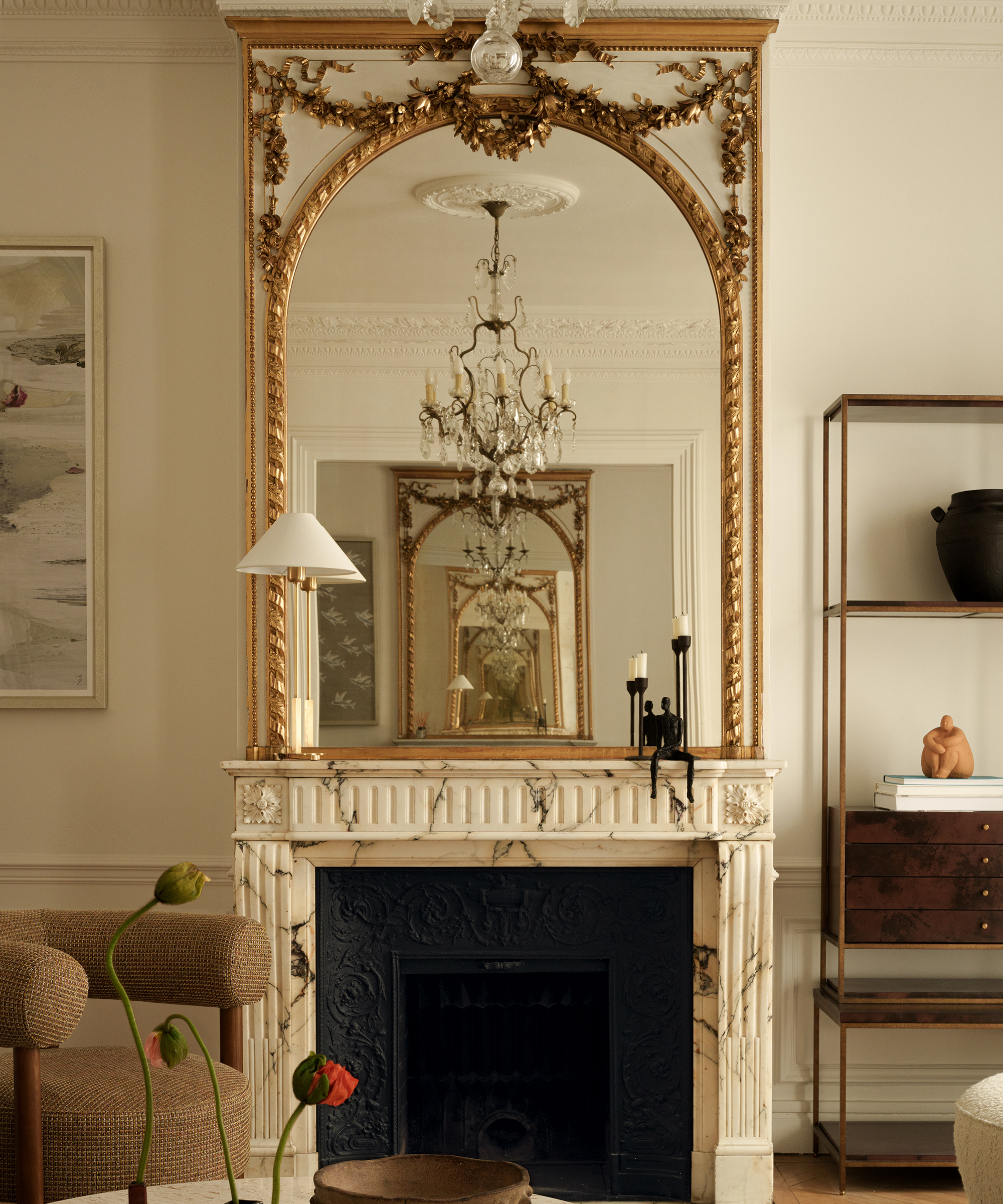 fireplace with table lamp on it and a decorative gilt mirror
