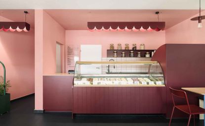 Pink ice-cream counter with jars of toppings on shelving behind