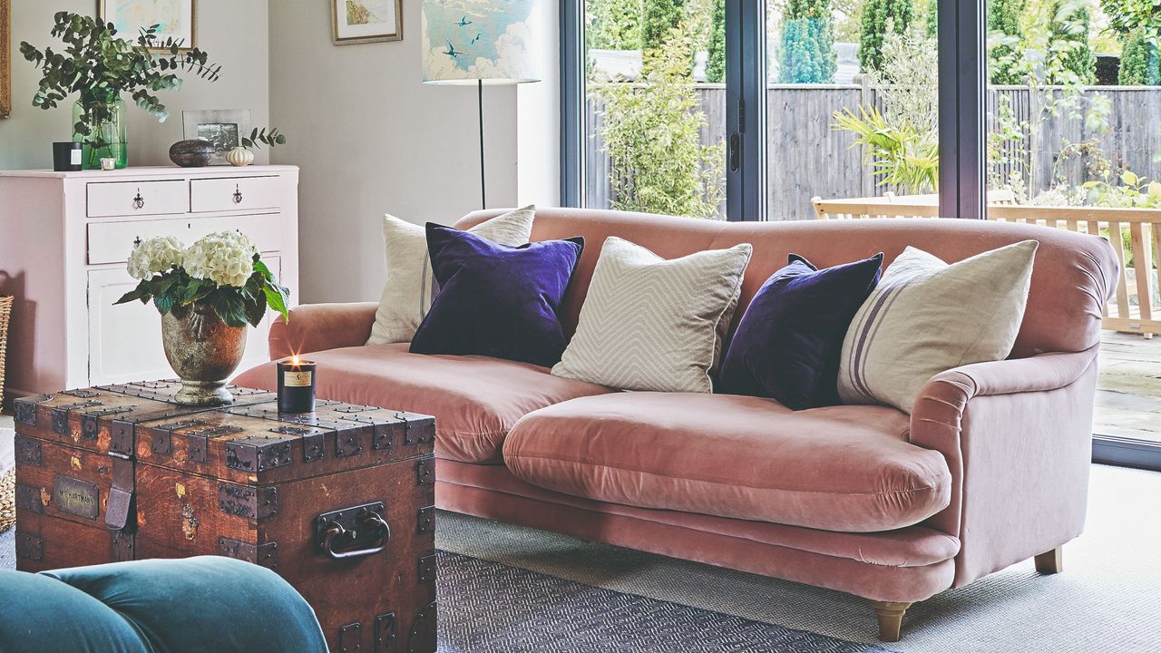 A living room with a pink velvet sofa and contrasting scatter cushions