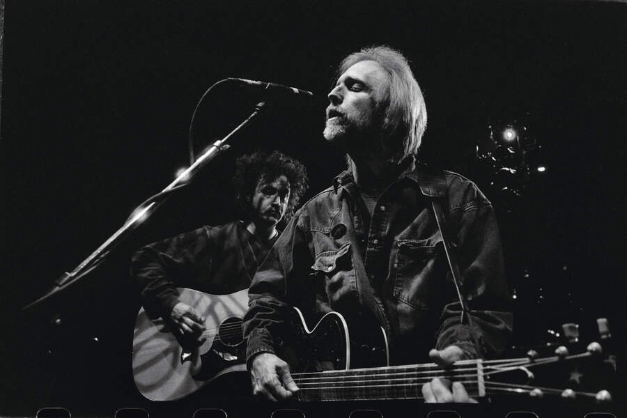 Tom Petty singing with an acoustic guitar