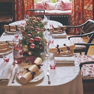 A Christmas table with a bauble-decorated garland used as a centrepiece