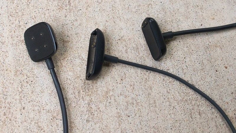 Three Fitbit Luxe chargers on a light carpeted floor
