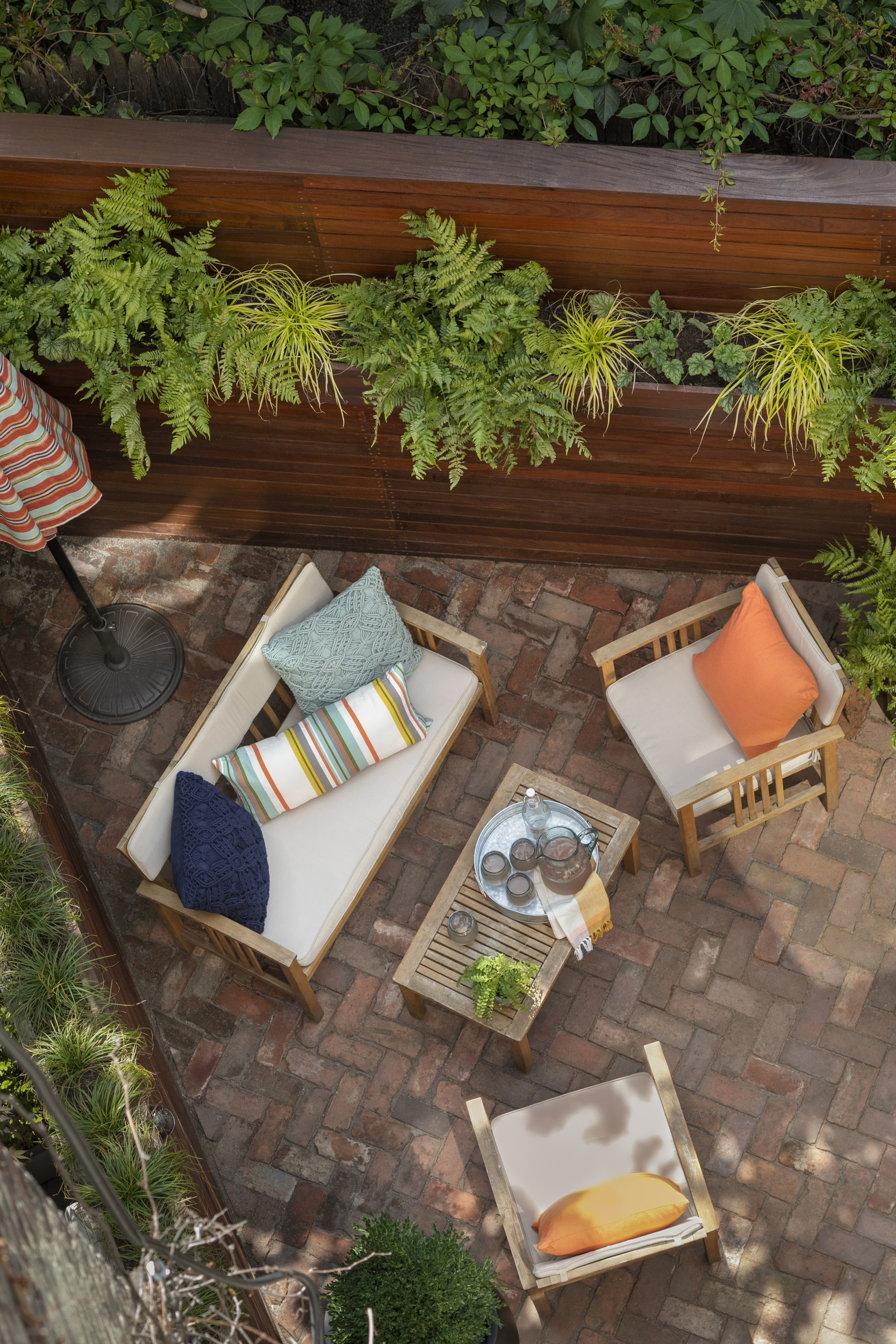 An aerial view of a backyard patio with a high fence and a garden furniture set