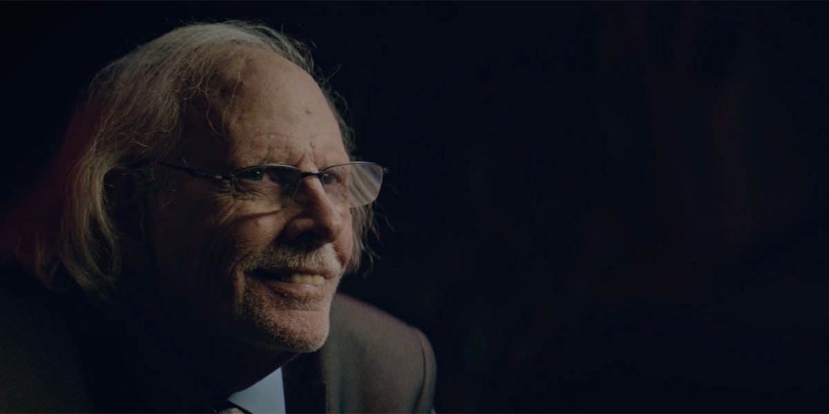 Bruce Dern with a suit on, smiling in an amused way with himself.