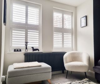 white window shutters in living room with white armchair