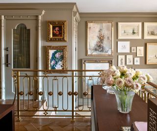 stairway with bronze rail and taupe walls with gallery wall of paintings