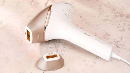 A closeup image of the Philips Lumea IPL hair removal machine lying on a counter next to its accessory