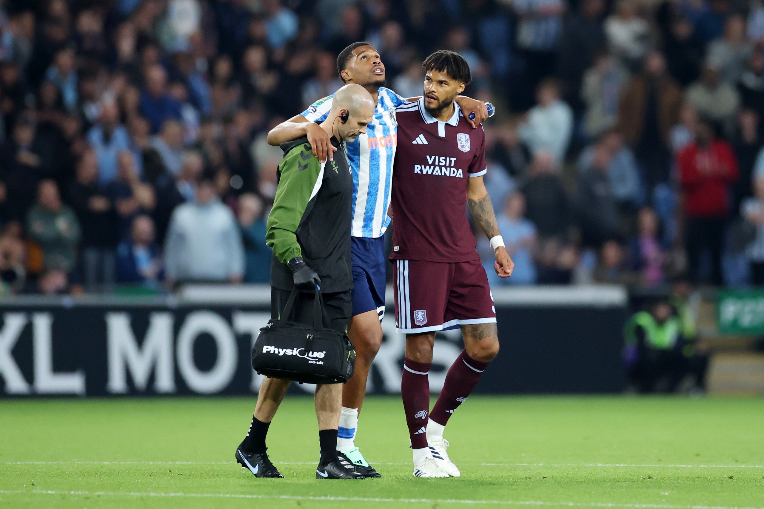 Coventry City's Aurele Amenda is helped off the pitch by Aston Villa defender Tyrone Mings