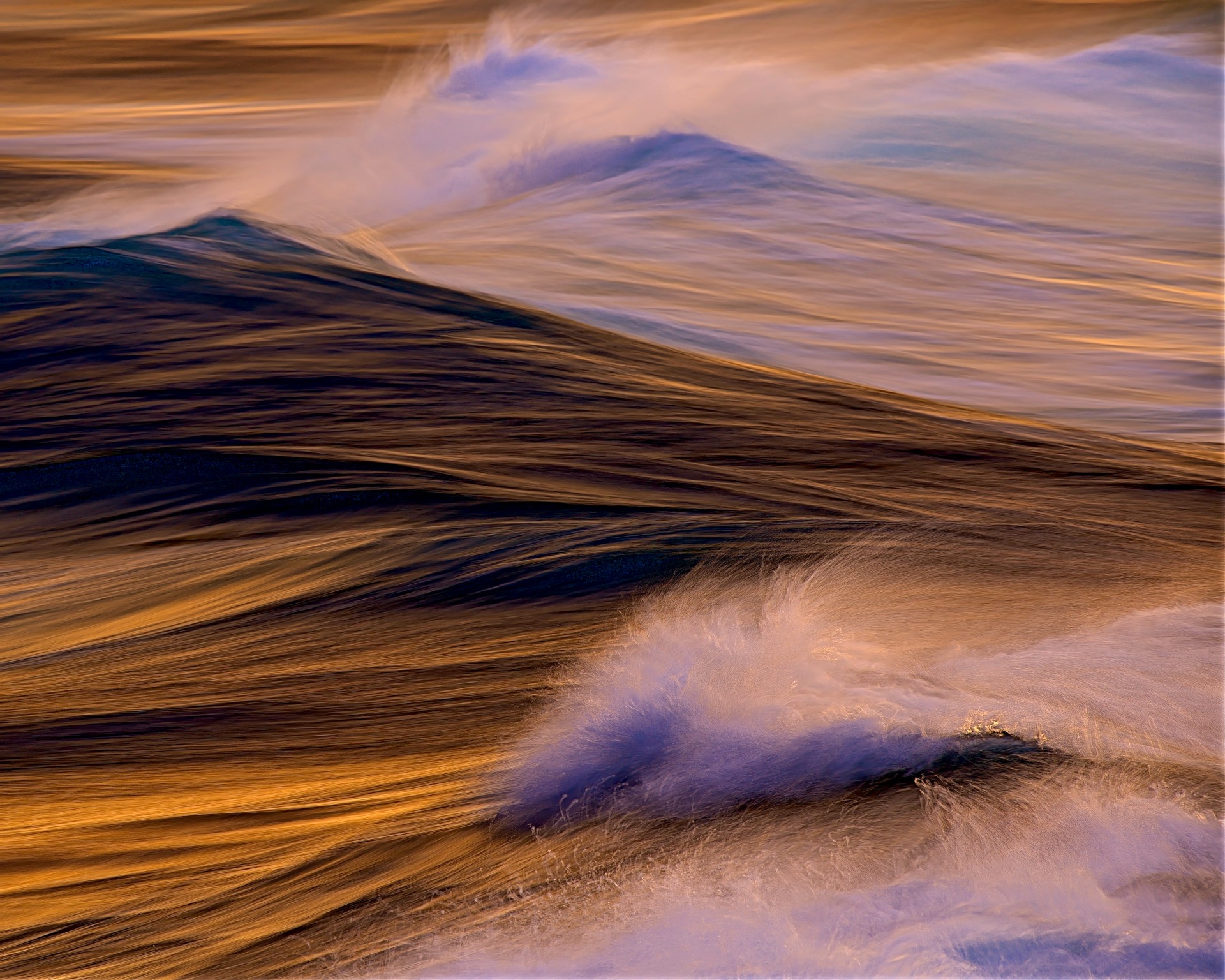 A painterly, long-exposure seascape featuring deep amber and golden waves that appear like liquid silk, crested by soft, misty white sea spray tinted with violet hues.