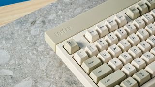 The Lofree Block keyboard on a stone surface with a blue wall in the background.