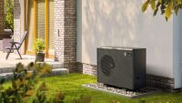 A black outdoor heat pump positioned against a wall 