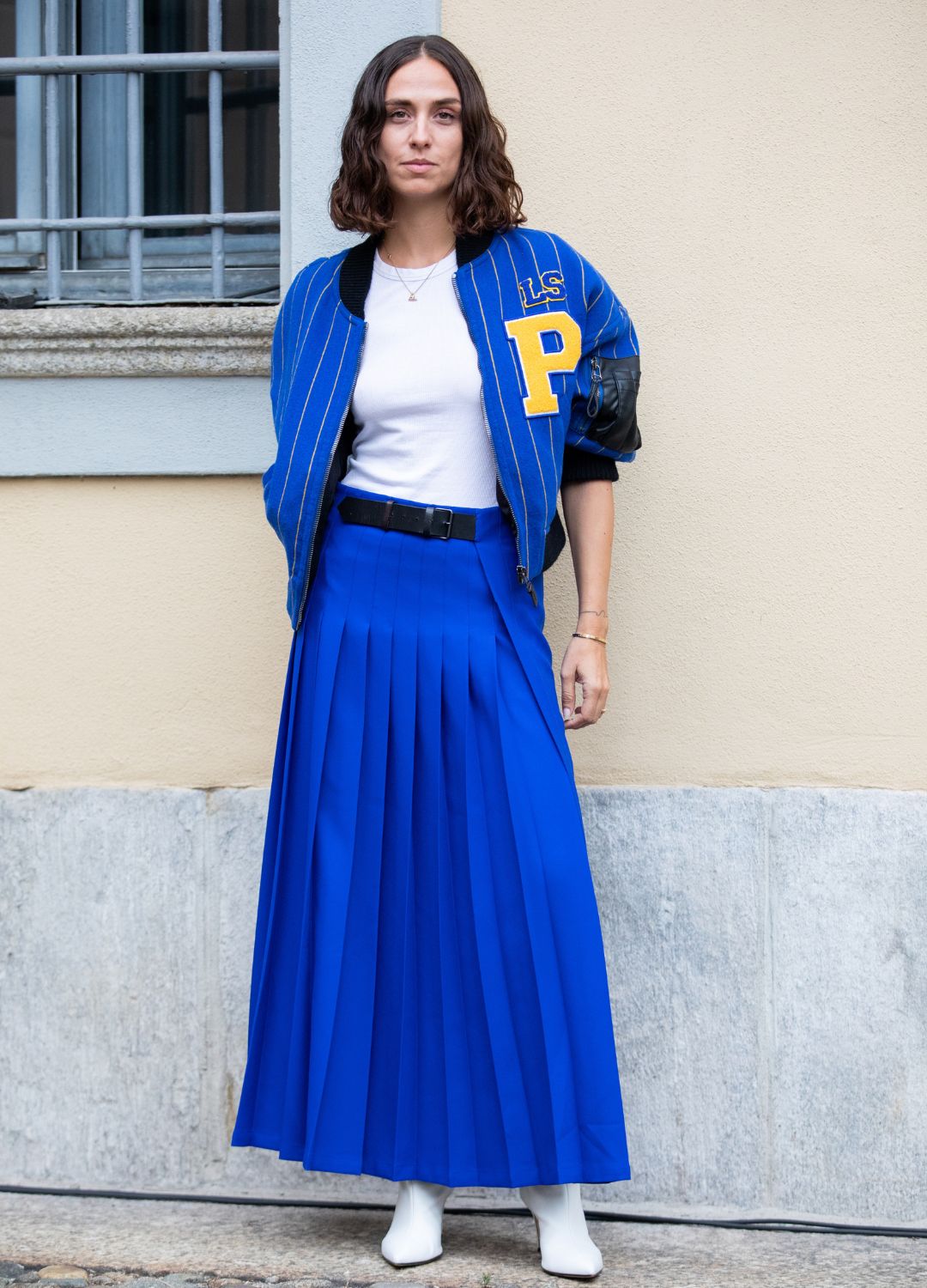 Erika Boldrin outside Philosophy fashion show wearing a long pleated blue skirt and a baseball striped blue jacket during the Milan Fashion Week - Spring / Summer 2022 on September 25, 2021 in Milan, Italy