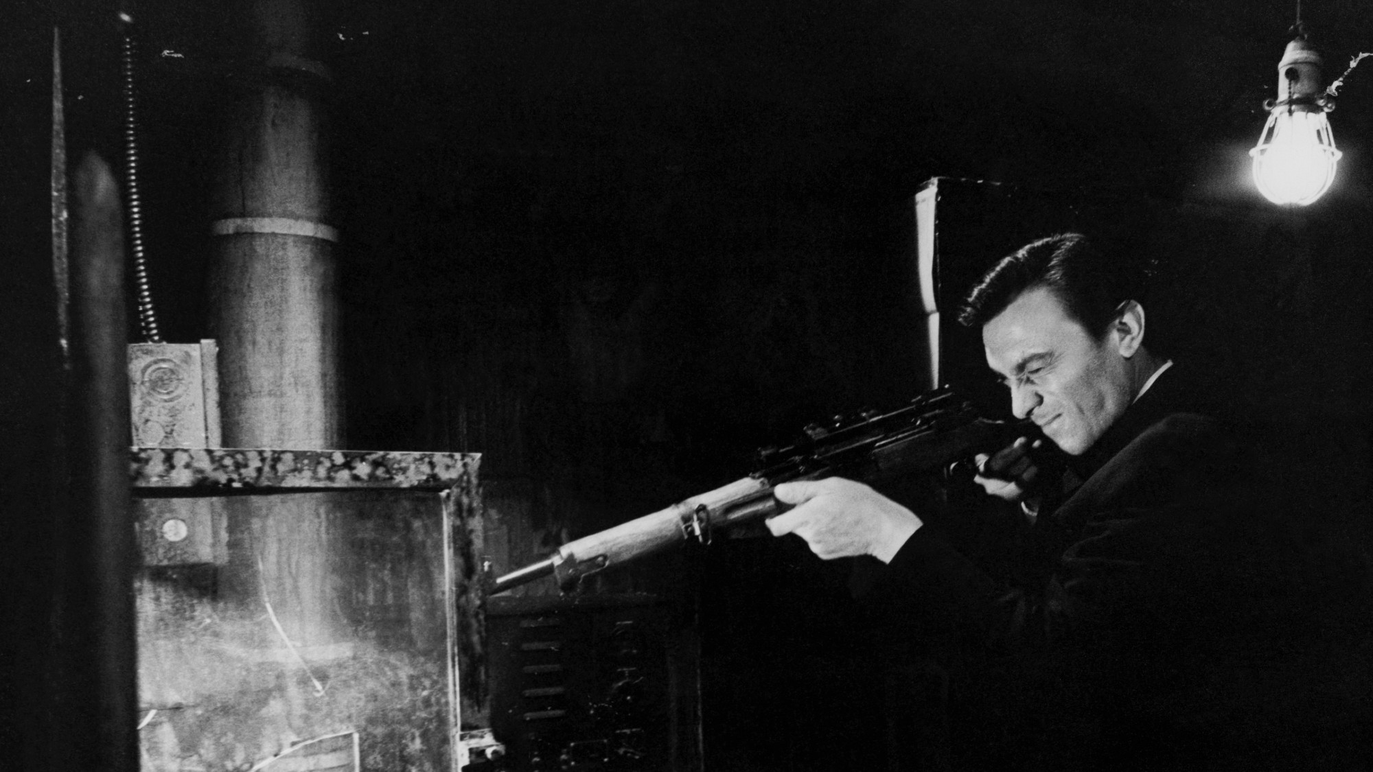 a still from &lsquo;The Manchurian Candidate.&rsquo; Raymond Shaw as played by Laurence Harvey shoots a gun at a contraption with water in it