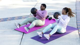 Two women outside doing the best ab exercises on yoga mat