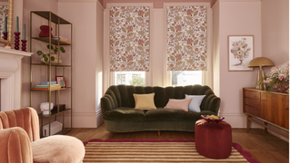 living room with stripy rug, wooden flooring, pink walls, floral blinds and green velvet sofa