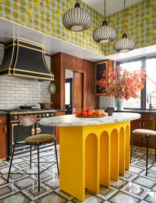 A kitchen with a yellow island and metallic chimney