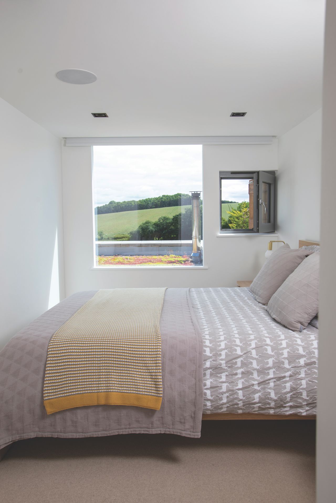 In the new addition, the master bedroom features a window with wood shutter, which allows air to circulate. Meanwhile, the fixed window overlooks the sedum green roof to the kitchen extension.