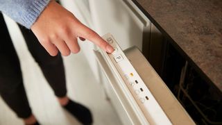 woman turning on dishwasher with finger