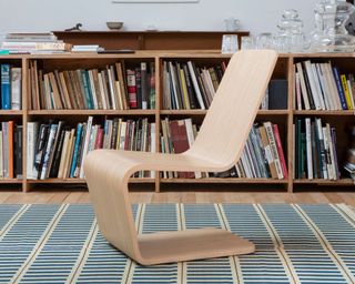 Twentytwentyone wooden chair on striped rug in front of bookcase