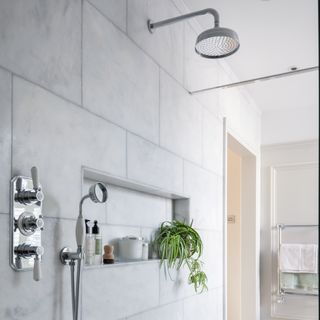 White bathroom walls with overhead silver shower and wall attachment