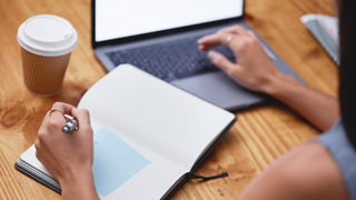 Woman writing in notepad while researching