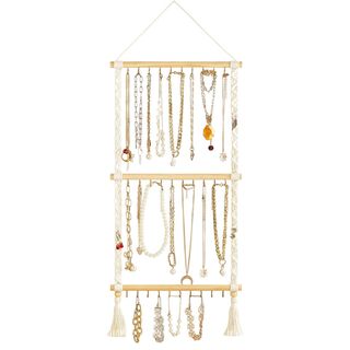 A macrame and wooden jewelry organizer is full of jewelry