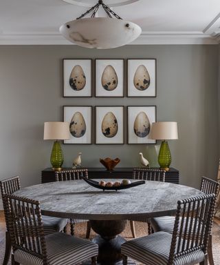 round dining table with six prints above and two lamps on sideboard