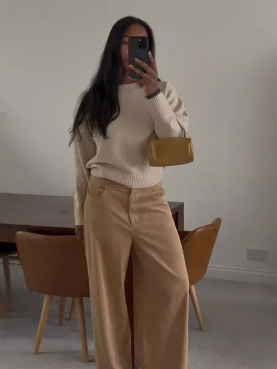 Woman wears beige jumper and camel jeans