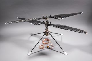 a small, four-rotor drone sits on a grayish-white surface