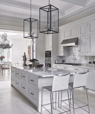 All white kitchen with kitchen island along the center and metal frame rectangular lantern ceiling lights