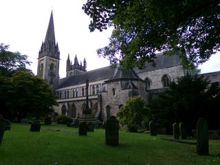 Outside of a large church surrounded by a grassy lawn and trees