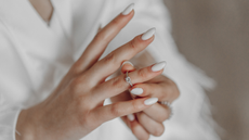 A woman with white nails putting a ring on