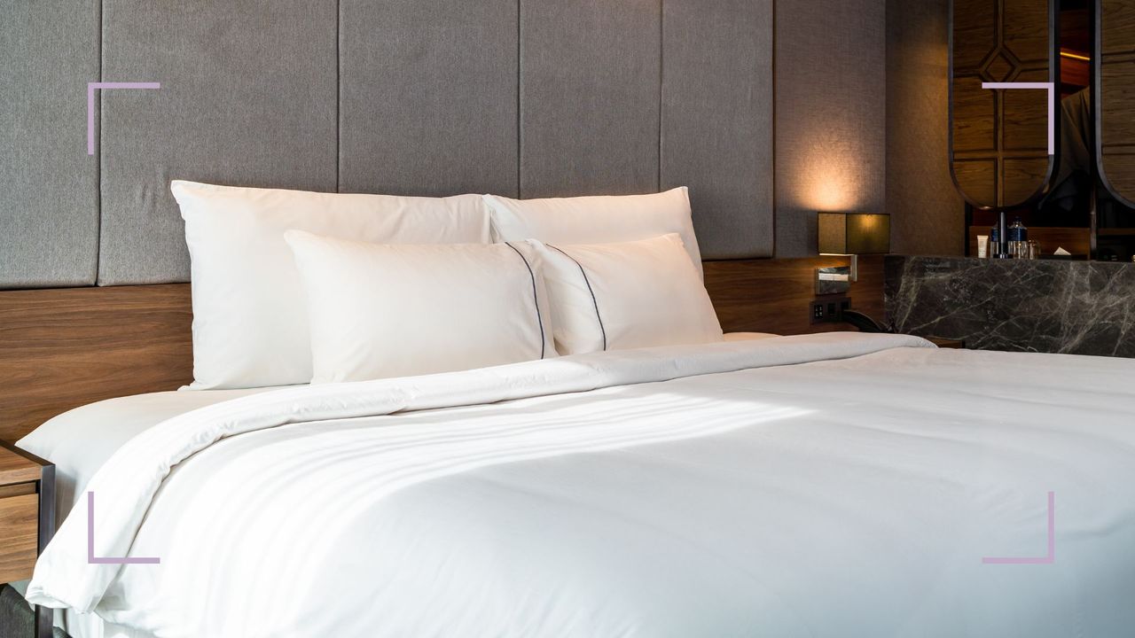 Luxury hotel room with a freshly bad bed with hotel pillows propped up against a wooden headboard