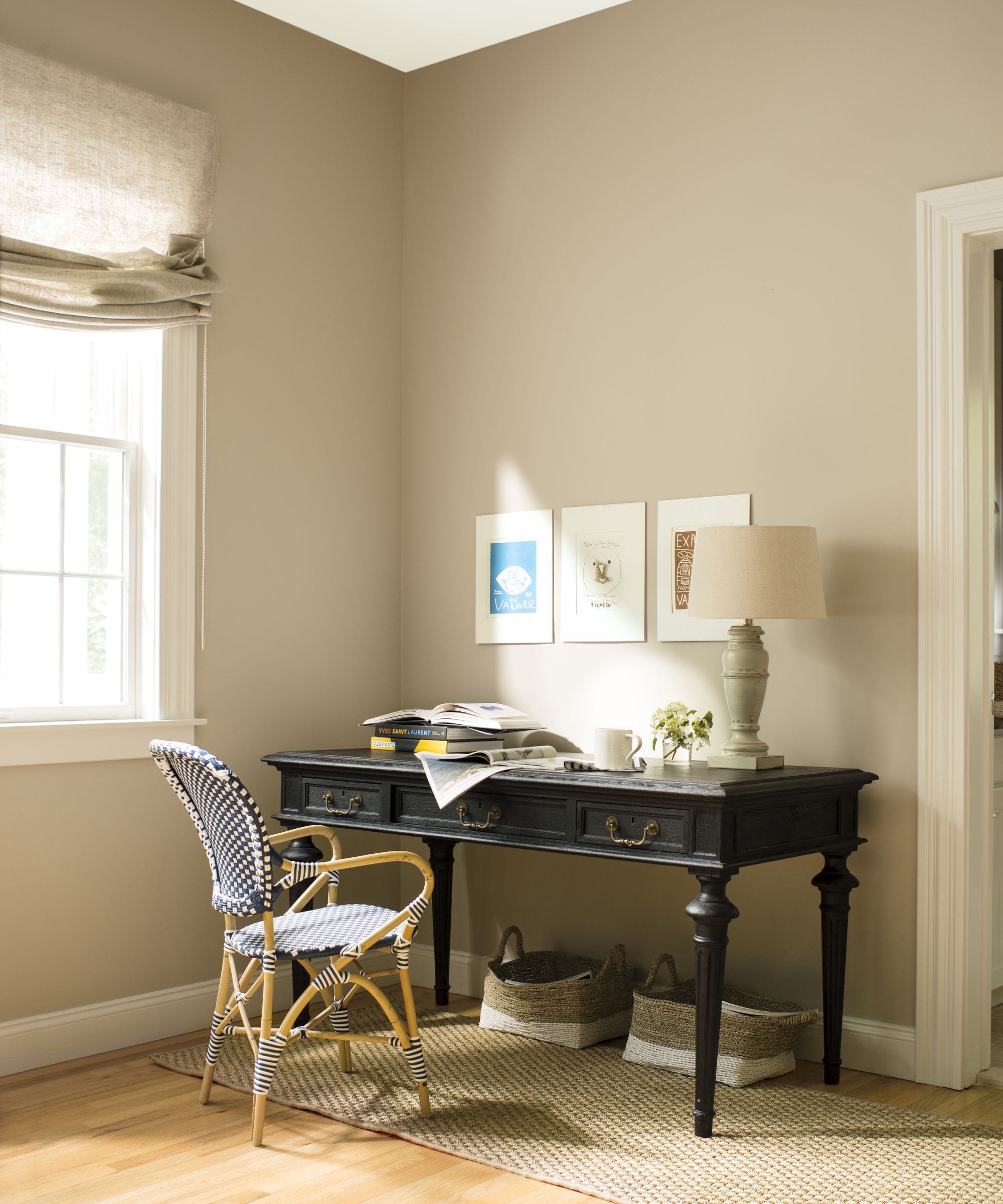beige walls in a room with a black desk next to a window with beige roman blinds