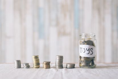 Stacked coins and coins in a glass jar with label written "toys"