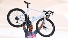 Mathieu van der poel lifting his bike up over his head after crossing the line and winning the 2025 Paris Roubaix