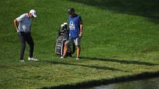 Phil Mickelson and his caddie look down at the rough near water at Quail Hollow during the 2025 PGA Championship