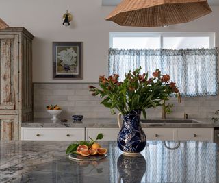 vintage kitchen with a floral cafe curtain and blue marble countertops