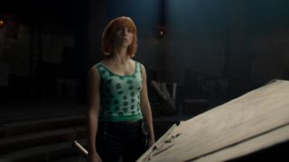 Emily Rudd as Nami stands in darkness in still from Netflix's One Piece