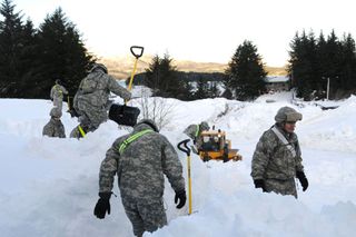 Alaska National Guardsmen clear a building roof in Cordova, near Anchorage, on Jan. 9.