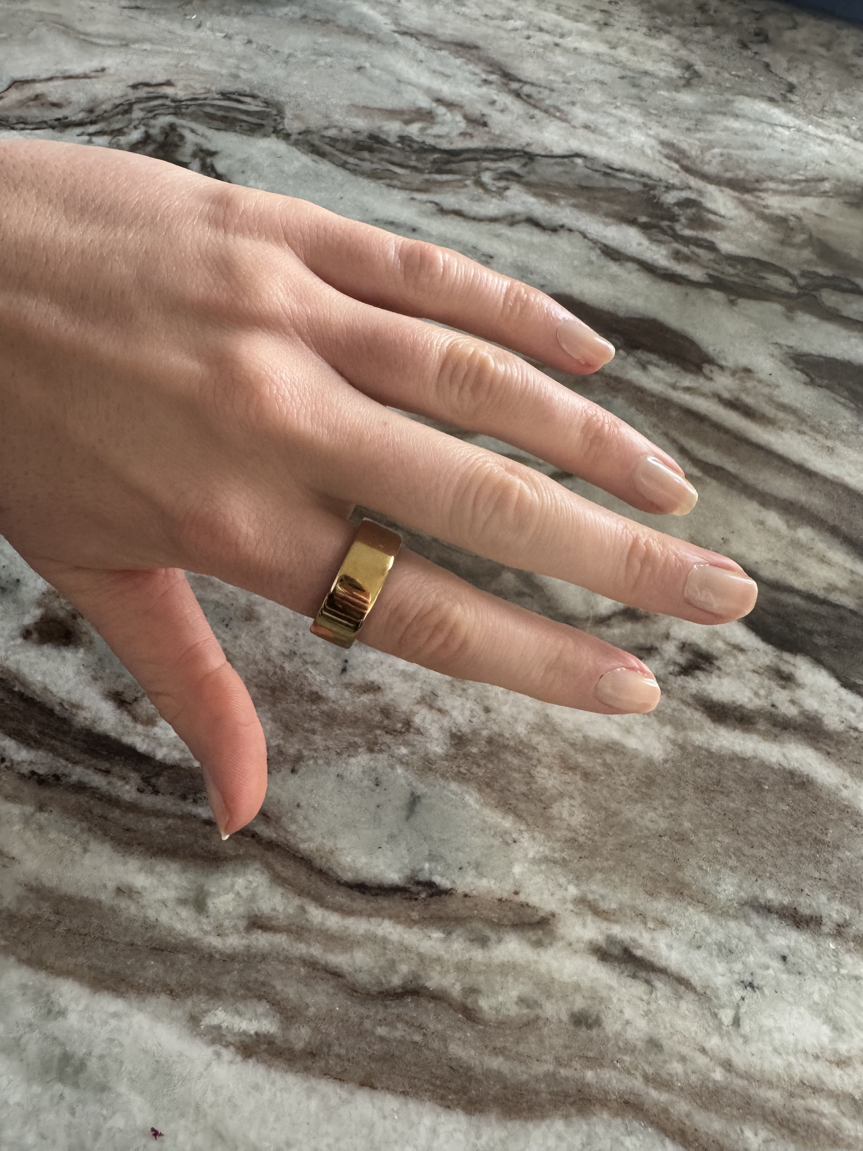 A picture of Eleanor's hand wearing the Oura Ring 4 in Gold, wearing a size 7
