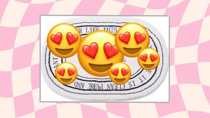 White bath mat on pink checkered background with heart eyes emoji hiding the bath mat