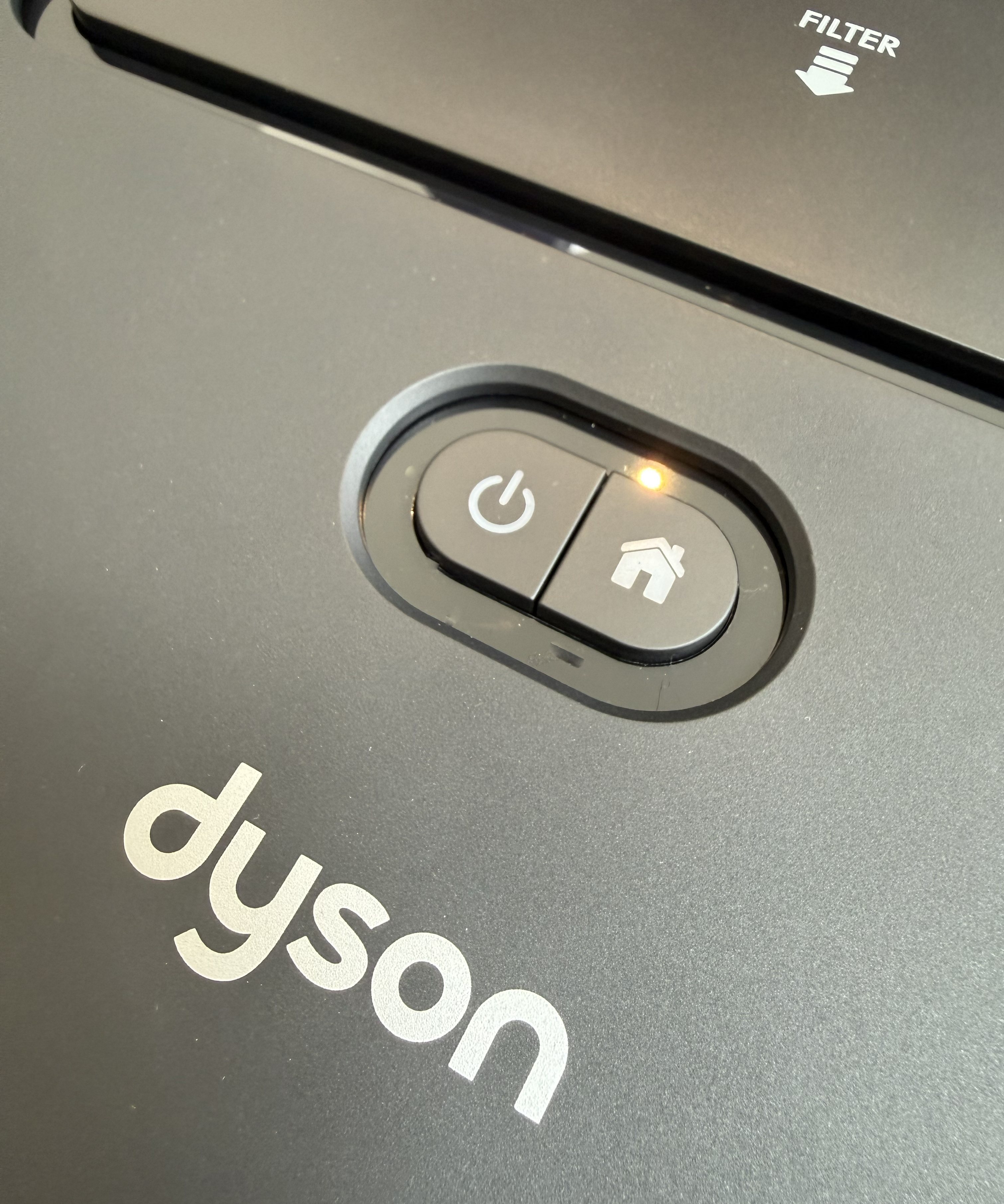 Close-up of the Dyson Spot+Scrub Ai power and home buttons with an amber charging light