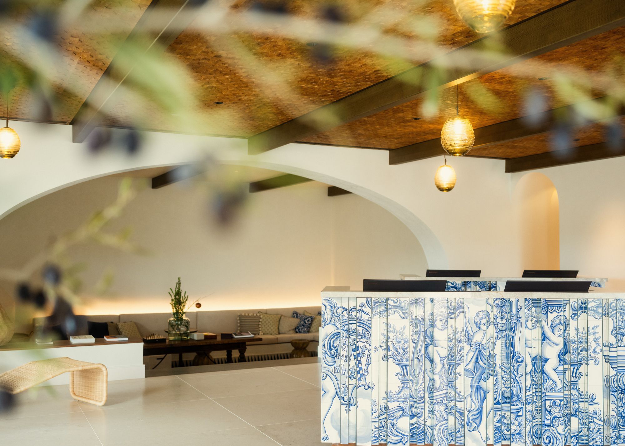 The reception area of Viceroy Ombria Algarve with a Portuguese inspired tiled reception table, wood covered ceilings and arched entryways 